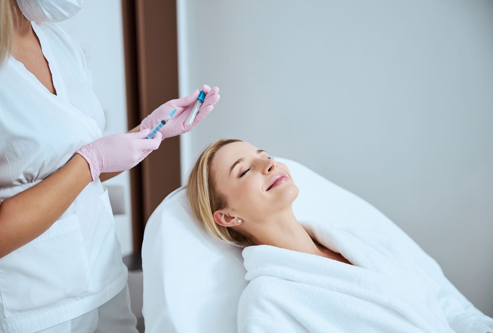 Aesthetic treatment being administered to a woman lying on a treatment bed.
